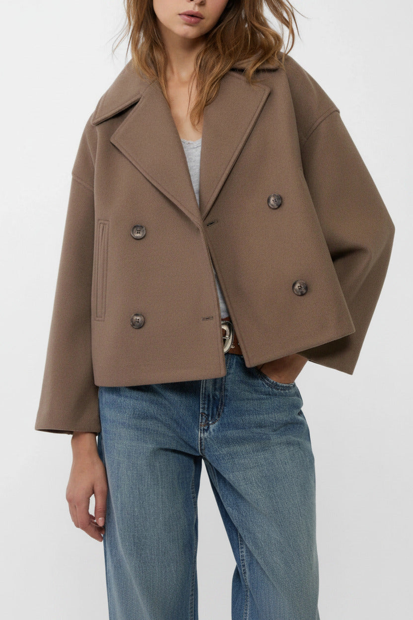 Person wearing a brown coat and blue jeans on a white background