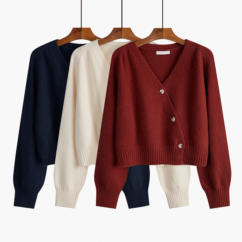 Three cardigans in navy, white, and red on hangers against a white background